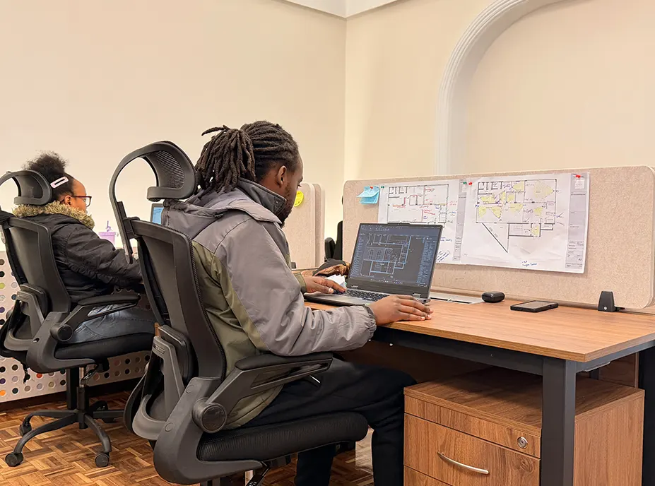 Two members of the studio team working at their desks