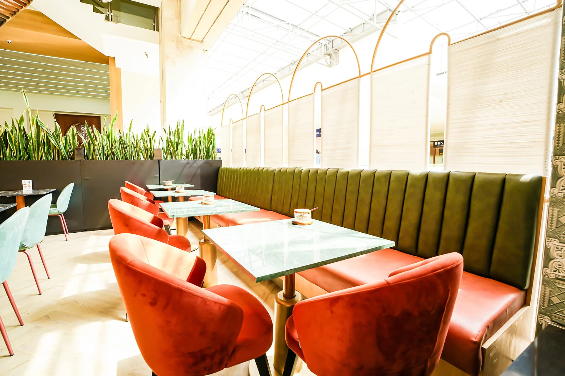 Green banquette and marble tables by the arched screen