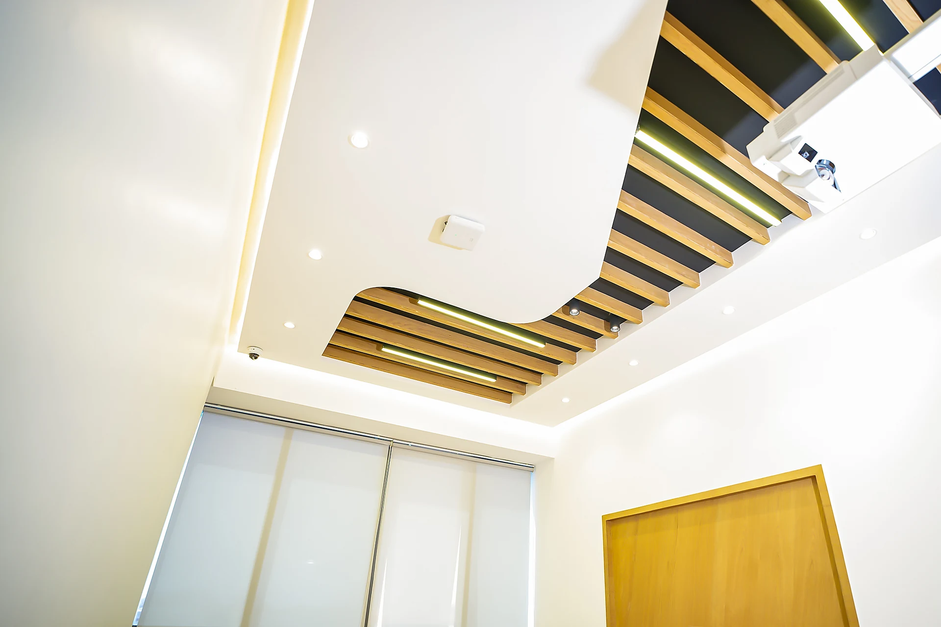 Curved bulkhead ceiling with timber slats and linear lighting