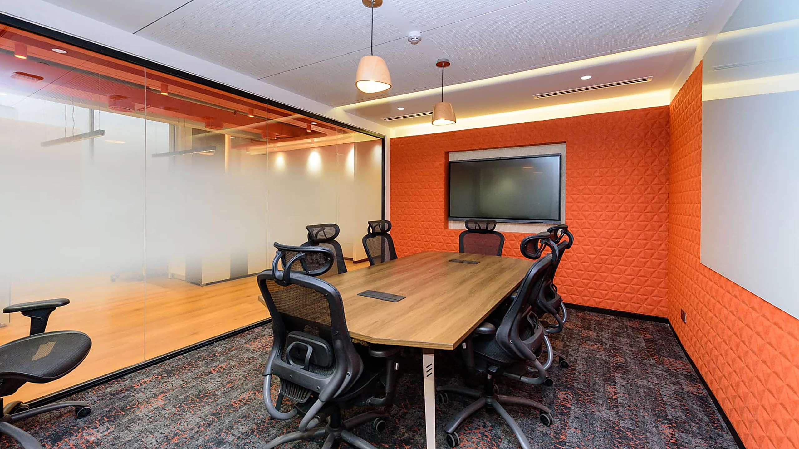 Rworld meeting room with orange acoustic wall, timber table and screen